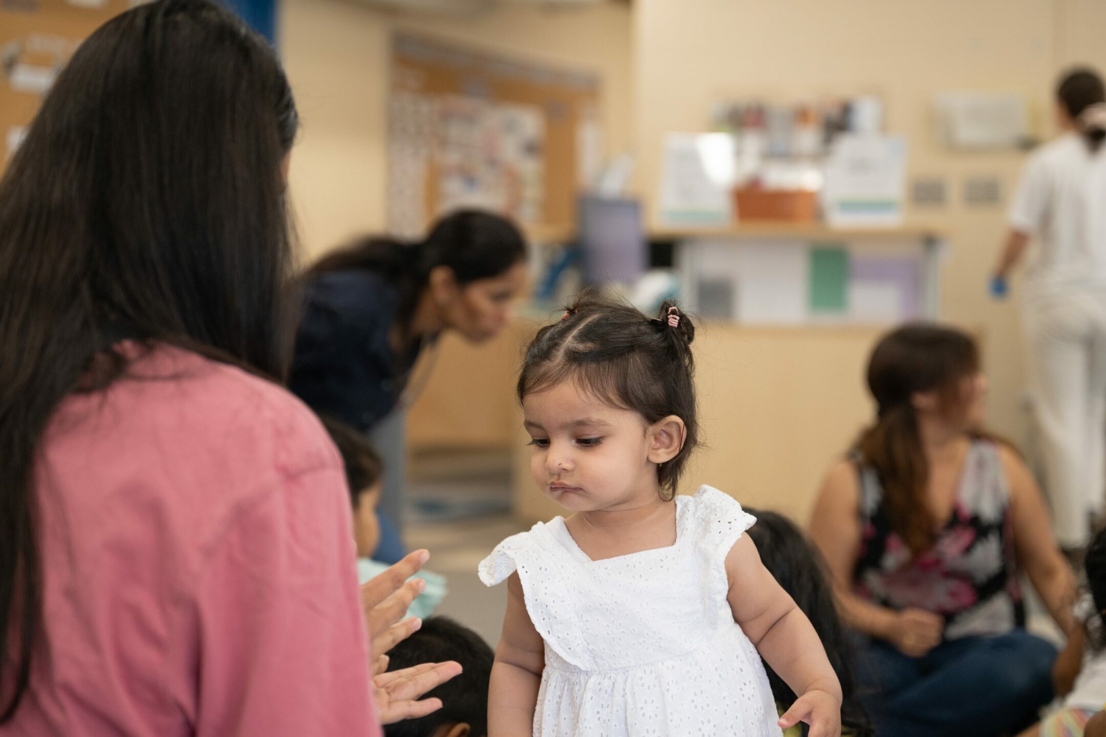 A toddler enjoying story time at BrightStart while looking at a young woman's hands.