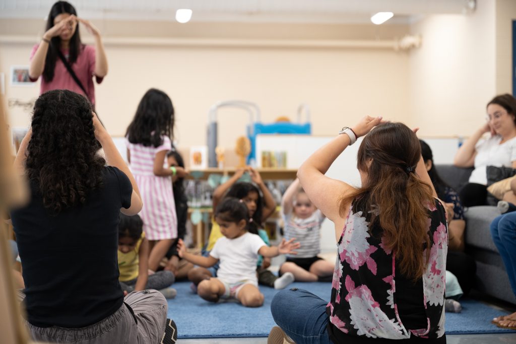 A group of little children is activity engaged in songs with actions at BrightStart with caregivers.