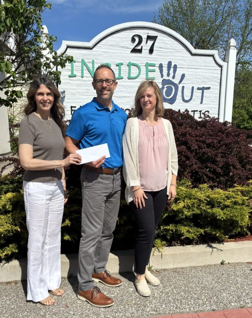 Photo of cheque presentation to Teresa Colasanti from Inside Out Chiropractic, taken in front of the business sign