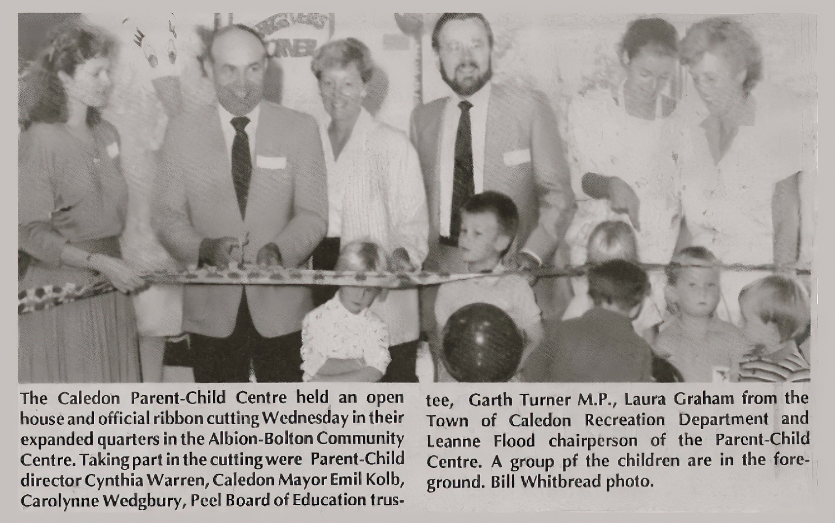 This newspaper clipping shows a ribbon-cutting event for the Caledon Parent-Child Centre’s expansion at the Albion-Bolton Community Centre. Present are director Cynthia Warren, Caledon Mayor Emil Kolb, Carolynne Wedgbury from the Peel Board of Education, Garth Turner M.P., and Leanne Flood, chair of the Parent-Child Centre. Children are seen in the foreground, marking this milestone for the community.