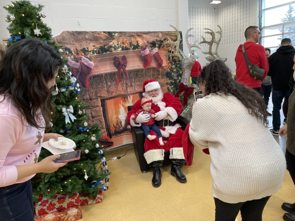 Photo of a parent taking a photo of a child on Santa's lap at Snowflake Social 2024